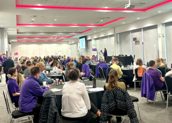 A photo of our conference on the day, and Alison speaking on stage to attendees